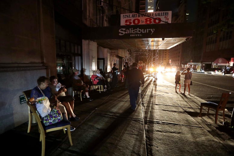 People sit outside a midtown hotel after a power outage left large parts of the West Side of Manhattan without power July 13, 2019. NYC power outage