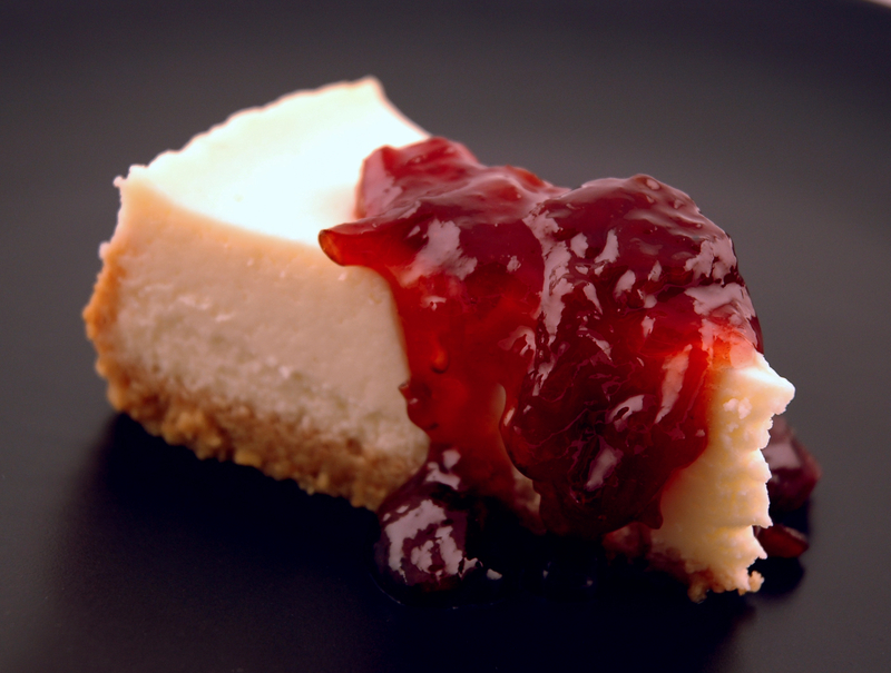 A slice of cheesecake topped with a cherry compote A slice of cheesecake topped with a cherry compote