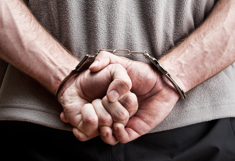 Criminal hands locked in handcuffs. Close-up view Criminal hands locked in handcuffs. Close-up view