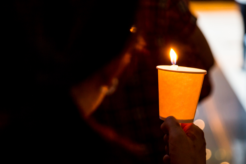 A mourner holds a candle at a vigil. A mourner holds a candle at a vigil.