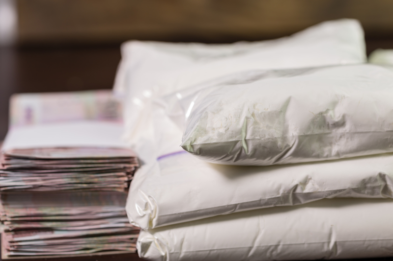 Stash of heroin drugs on table in transparent bags with money in piles Stash of heroin drugs on table in transparent bags with money in piles