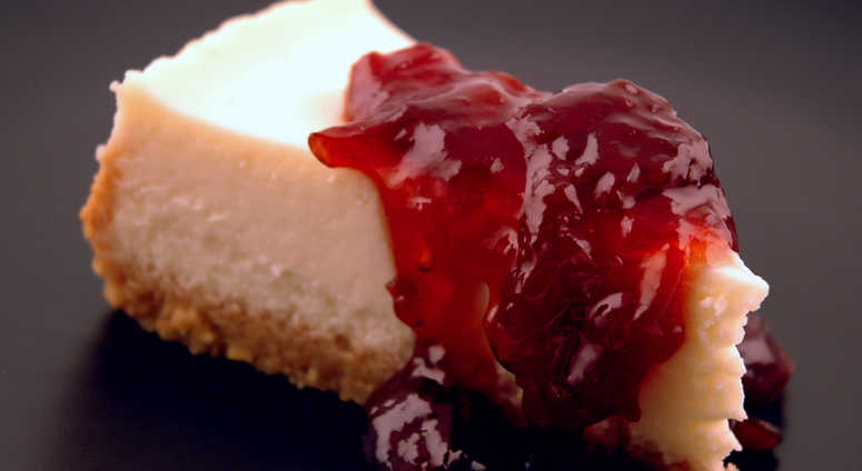 A slice of cheesecake topped with a cherry compote A slice of cheesecake topped with a cherry compote