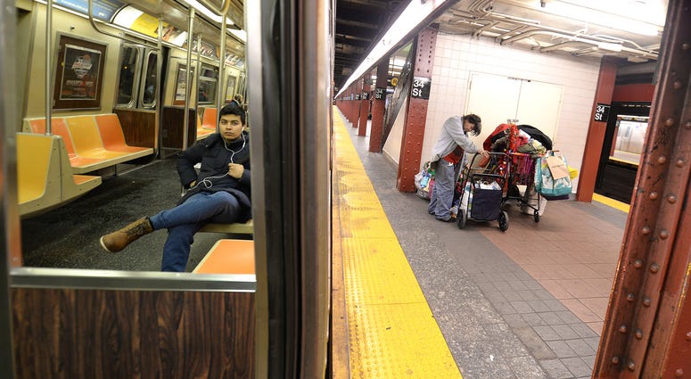 A man sits in a nearly empty subway car as a homeless person seeks shelter on a the subway platform Homeless in subway