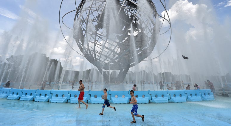 Children plays in the Unisphere fountain to cool of from temperatures approaching 100 degrees fahrenheit, with “feels like” temperature of 110 degrees, in Flushing Meadows-Corona Park in the New York City borough of Queens. 2019 heat wave