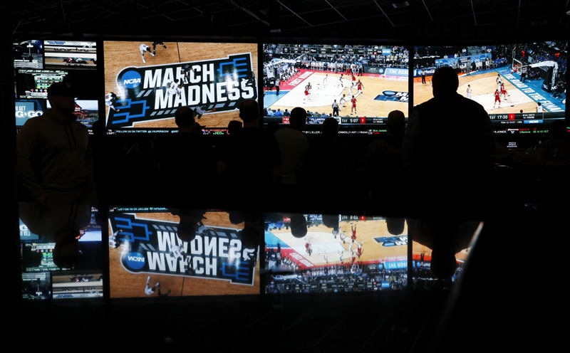 In this March 15, 2018 photo, people watch coverage of the first round of the NCAA college basketball tournament at the Westgate Superbook sports book in Las Vegas. In this March 15, 2018 photo, people watch coverage of the first round of the NCAA college basketball tournament at the Westgate Superbook sports book in Las Vegas.