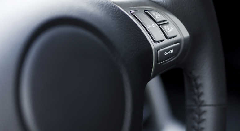 A close-up of cruise control buttons on a steering wheel. Shallow depth of field, focus on buttons. A close-up of cruise control buttons on a steering wheel. Shallow depth of field, focus on buttons.