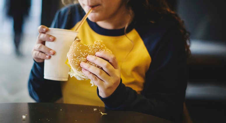 Overweight young person eating fast food. Obesity