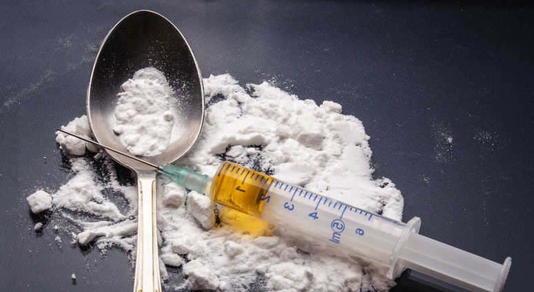 Drug syringe and cooked heroin on spoon Drug syringe and cooked heroin on spoon