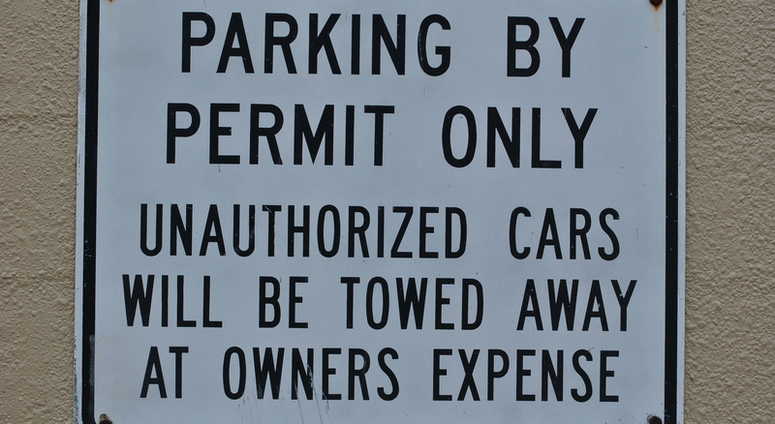 Parking By Permit Only Unauthorized Cars Will Be Towed Away At Owners Expense sign. Parking By Permit Only Unauthorized Cars Will Be Towed Away At Owners Expense sign.