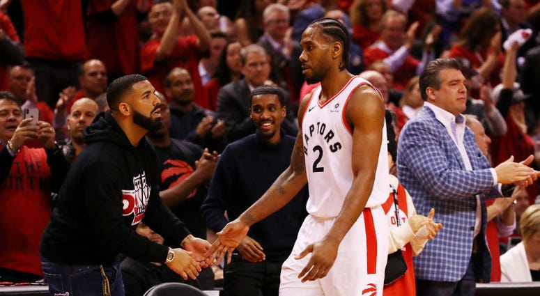Rapper Drake high fives Raptors guard Kawhi Leonard. Drake_Kawhi_Leonard