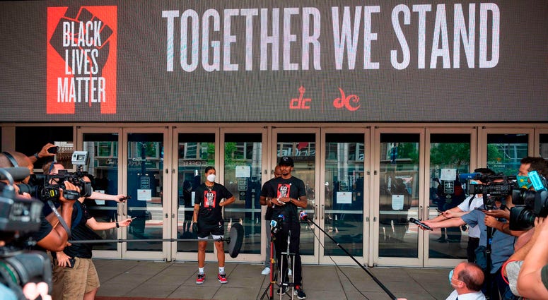 Bradley Beal speaks in front of Capital One Arena and a video board that prominently displays 'Black Lives Matter' and 'Together We Stand' DC's Juneteenth march to the Martin Luther King, Jr. Memorial