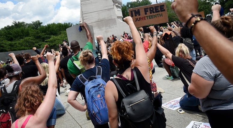 Demonstrators kneel at the Martin Luther King, Jr. Memorial DC's Juneteenth march to the Martin Luther King, Jr. Memorial