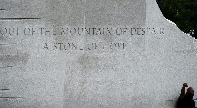 A demonstrator holds up his fist at the MLK Memorial, under a quote that reads: 'Out of the mountain of despair, a stone of hope' DC's Juneteenth march to the Martin Luther King, Jr. Memorial