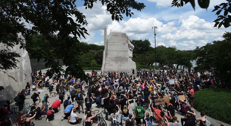 Demonstrators kneel and hold up their fists at the Martin Luther King, Jr. Memorial DC's Juneteenth march to the Martin Luther King, Jr. Memorial