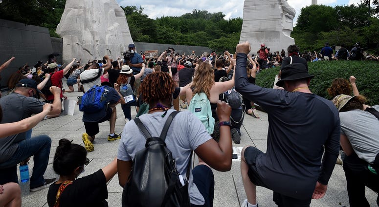 Demonstrators kneel and hold up their fists at the Martin Luther King, Jr. Memorial DC's Juneteenth march to the Martin Luther King, Jr. Memorial