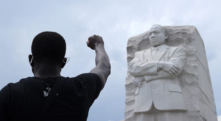 A man kneels and raises his fist in the air for eight minutes and 46 seconds – the time that George Floyd was pinned under a police officer's knee – during a march and protest to mark the Juneteenth holiday DC's Juneteenth march to the Martin Luther King, Jr. Memorial
