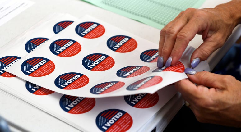 Poll workers hand out 'I voted' stickers at a local precinct I-voted-sticker