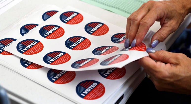 Poll workers hand out 'I voted' stickers at a local precinct I-voted-sticker