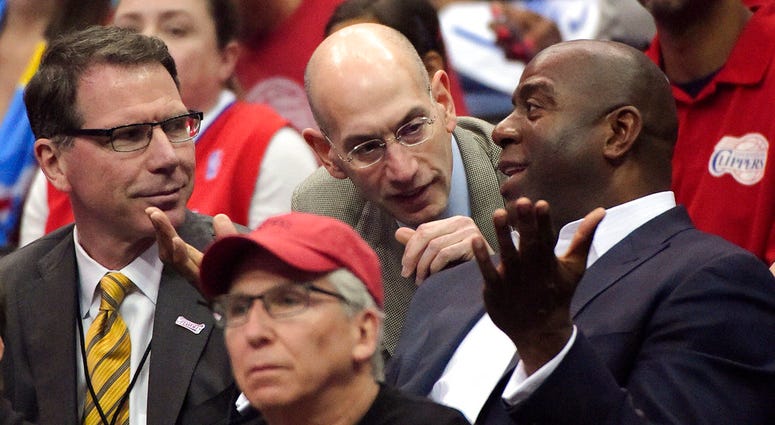 In this May 11, 2014, file photo, NBA Commissioner Adam Silver, center, talks with Magic Johnson, right, as Kiki Vandeweghe looks on as they watch the Los Angeles Clippers play the Oklahoma City Thunder in the first half of Game 4 of the Western Conferenc The NBA will experiment with a coaches' challenge for summer league games, one where teams will have the ability to seek a review of certain calls in the final 2 minutes of regulation and overtime. Coaches will have to call a time-out before live play res