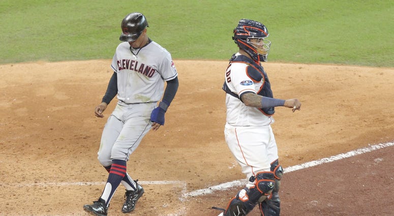 Cleveland Indians shortstop Francisco Lindor (left) scores on a ground out by second baseman Jose Ramirez (not pictured) against Houston Astros catcher Martin Maldonado (right) during the sixth inning in game one of the 2018 ALDS Jose Ramirez Game 1 ALDS