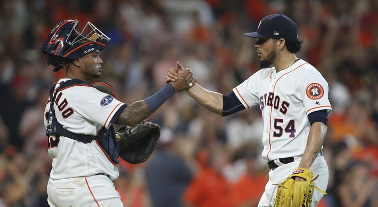 Houston Astros catcher Martin Maldonado (15) and relief pitcher Roberto Osuna (54) celebrate after defeating the Cleveland Indians in game one of the 2018 ALDS playoff baseball series at Minute Maid Park. Houston Astros catcher Martin Maldonado and relief pitcher Roberto Osuna Game 1 ALDS