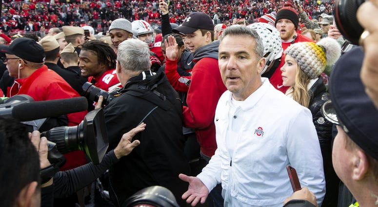Ohio State Buckeyes head coach Urban Meyer searches the crowd as fans rush the field after the game against the Michigan Wolverines at Ohio Stadium. Urban Meyer