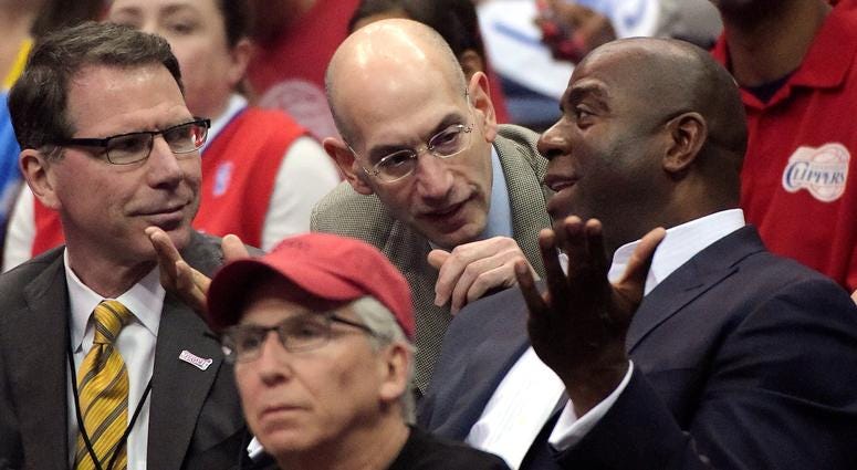 n this May 11, 2014, file photo, NBA Commissioner Adam Silver, center, talks with Magic Johnson, right, as Kiki Vandeweghe looks on n this May 11, 2014, file photo, NBA Commissioner Adam Silver, center, talks with Magic Johnson, right, as Kiki Vandeweghe looks on