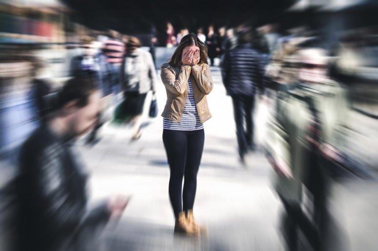 woman in crowd stressed, touching face