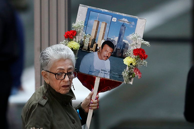Una mujer llega a una ceremonia por el 17mo aniversario de los atentados terroristas del 11 de septiembre de 2001, con una fotografía de Wilder Gómez, un colombiano que trabajaba como camarero en el restaurante Windows on the World, en el piso 103 del Wor Una mujer llega a una ceremonia por el 17mo aniversario de los atentados terroristas del 11 de septiembre de 2001, con una fotografía de Wilder Gómez, un colombiano que trabajaba como camarero en el restaurante Windows on the World, en el piso 103 del Wor