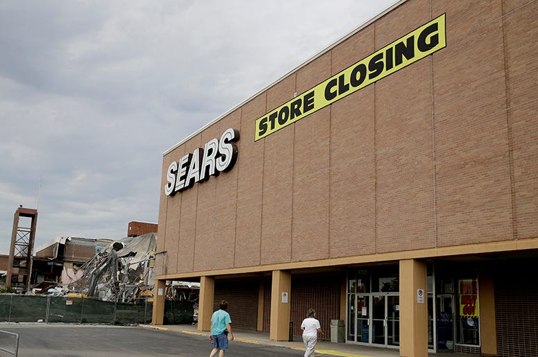 Esta foto de archivo del 8 de julio del 2017 muestra a gente caminando a una tienda de Sears que va a cerrar, ubicada al lado de un centro comercial que está siendo demolido en Overland Park, Kansas. Esta foto de archivo del 8 de julio del 2017 muestra a gente caminando a una tienda de Sears que va a cerrar, ubicada al lado de un centro comercial que está siendo demolido en Overland Park, Kansas.