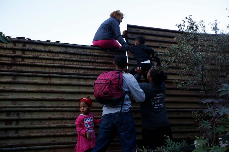 Migrantes hondureños se ayudan entre ellos para cruzar el muro fronterizo a San Diego, California, desde Tijuana, México, el sábado 15 de diciembre de 2018. Migrantes hondureños se ayudan entre ellos para cruzar el muro fronterizo a San Diego, California, desde Tijuana, México, el sábado 15 de diciembre de 2018.