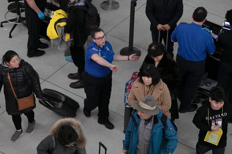 Una agente de la Administración de Seguridad en el Transporte, centro, da instrucciones a los pasajeros en un punto de revisión en el Aeropuerto Internacional John F. Kennedy, en Nueva York. Una agente de la Administración de Seguridad en el Transporte, centro, da instrucciones a los pasajeros en un punto de revisión en el Aeropuerto Internacional John F. Kennedy, en Nueva York.