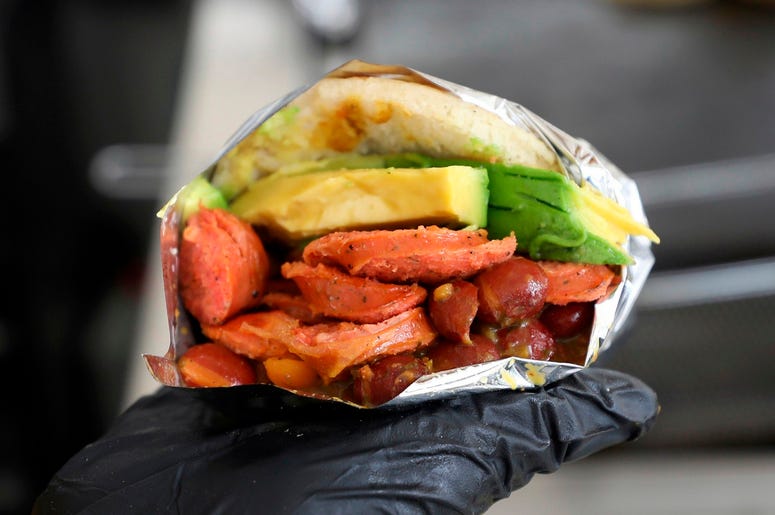 En esta imagen del 11 de junio de 2019, un empleado muestra una arepa venezolana hecha con ingredientes colombianos en el restaurante de comida rápida "Arepas Cafe" en Bogotá, Colombia. En esta imagen del 11 de junio de 2019, un empleado muestra una arepa venezolana hecha con ingredientes colombianos en el restaurante de comida rápida "Arepas Cafe" en Bogotá, Colombia.