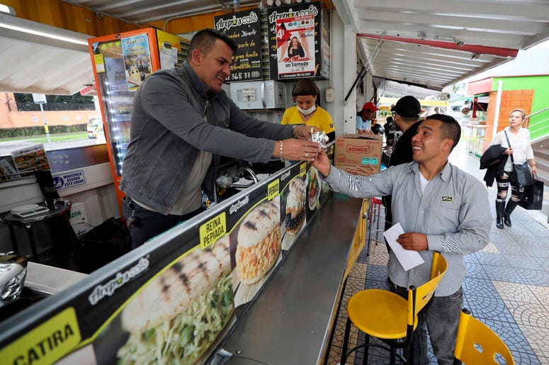 n esta imagen del 11 de junio de 2019, Gerson Brice o, propietario del restaurante de comida r pida "Arepas Cafe", sirve a un cliente en Bogotá, Colombia, el martes 11 de junio de 2019 n esta imagen del 11 de junio de 2019, Gerson Brice o, propietario del restaurante de comida r pida "Arepas Cafe", sirve a un cliente en Bogotá, Colombia, el martes 11 de junio de 2019