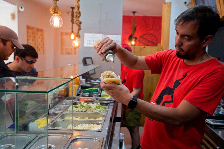 En esta imagen del 19 de junio de 2019, el cocinero y propietario del restaurante Arepa Ol , Edgar Rodr guez, de Venezuela, prepara una Arepa Iberia con jam n serrano, tomate y aceite de oliva en Madrid, Espa a. En esta imagen del 19 de junio de 2019, el cocinero y propietario del restaurante Arepa Ol , Edgar Rodr guez, de Venezuela, prepara una Arepa Iberia con jam n serrano, tomate y aceite de oliva en Madrid, Espa a.