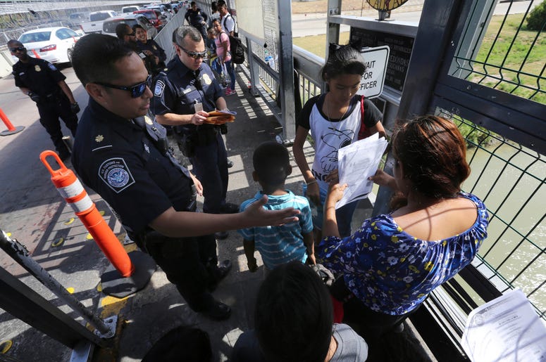 Foto de archivo del 17 de julio de 2019 de un agente fronterizo estadounidense verificando los documentos de migrantes antes de ser llevados a solicitar asilo en Estados Unidos, en el Puente Internacional 1 en Nuevo Laredo, México. Foto de archivo del 17 de julio de 2019 de un agente fronterizo estadounidense verificando los documentos de migrantes antes de ser llevados a solicitar asilo en Estados Unidos, en el Puente Internacional 1 en Nuevo Laredo, México.