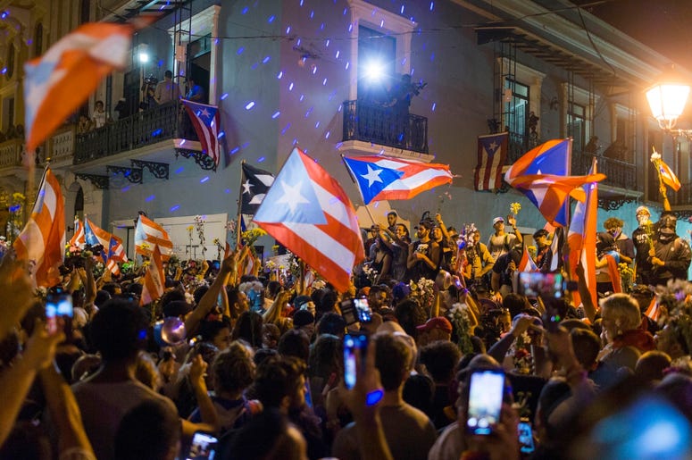 Gente celebrando ante la residencia oficial del gobernador de Puerto Rico, La Fortaleza, después de que el gobernador, Ricardo Rosselló, anunciara que dimitirá el 2 de agosto tras casi dos semanas de protestas, en San Juan, Puerto Rico, el jueves 25 de ju Gente celebrando ante la residencia oficial del gobernador de Puerto Rico, La Fortaleza, después de que el gobernador, Ricardo Rosselló, anunciara que dimitirá el 2 de agosto tras casi dos semanas de protestas, en San Juan, Puerto Rico, el jueves 25 de ju