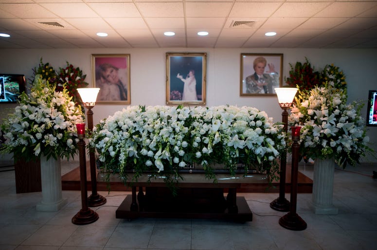 El ataúd con los restos del astrólogo de la televisión Walter Mercado, cubierto de lilas y rosas, es exhibido durante un velatorio público en el vecindario de Santurce, en San Juan, Puerto Rico, el miércoles 6 de noviembre de 2019. El ataúd con los restos del astrólogo de la televisión Walter Mercado, cubierto de lilas y rosas, es exhibido durante un velatorio público en el vecindario de Santurce, en San Juan, Puerto Rico, el miércoles 6 de noviembre de 2019.