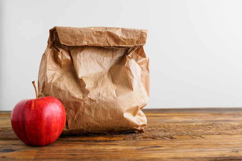 An apple next to brown paper bag lunch