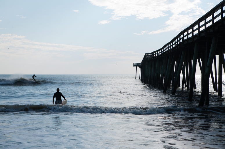 A man surfs near the Virginia Beach Fishing Pier A man surfs near the Virginia Beach Fishing Pier
