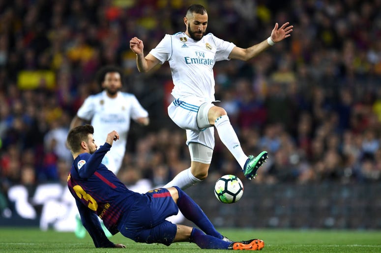 BARCELONA, SPAIN - MAY 06: Karim Benzema of Real Madrid is challenged by Gerard Pique of Barcelona during the La Liga match between Barcelona and Real Madrid at Camp Nou on May 6, 2018 in Barcelona, Spain.