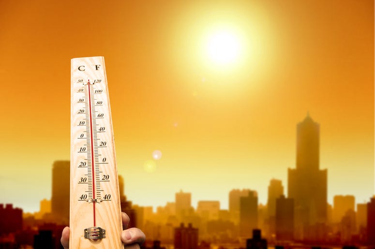 Thermometer shows high temperature with city in background