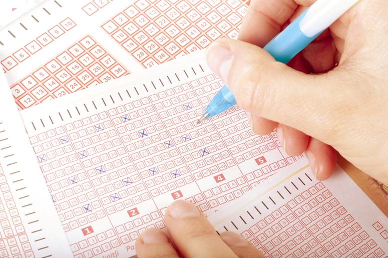 hand fills out lottery tickets with a pencil