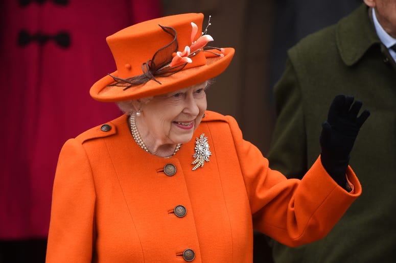 Queen Elizabeth II waves in an orange suit