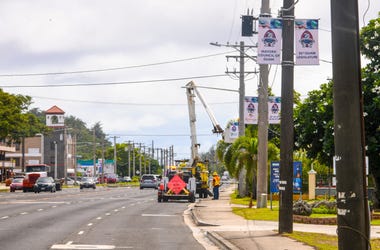 Guam Power Authority employees utilized the basket of a bucket truck to hang 75th Liberation banners, on utility poles along Marine Corps Drive, in H gat a on Tuesday, July 16, 2019. The section of the roadway is part of the Liberation Day Parade route sl