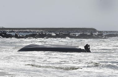 An approximately 20-foot center-console boat sits upside down in the surf near the west jetty on Okaloosa Island Monday morning. Destin Fire Rescue responded about 7:40 a.m. Monday to a distress call of a capsized boat with three passengers, all of whom a