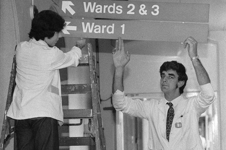 English actor Peter Mayhew (right) helps put up signs to the wards at King's College Hospital, where he works as an orderly, 3rd June 1977. Mayhew, who is 7'3'' tall English actor Peter Mayhew (right) helps put up signs to the wards at King's College Hospital, where he works as an orderly, 3rd June 1977. Mayhew, who is 7'3'' tall