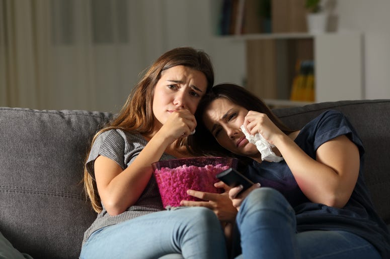 Two sad friends crying watching tv in the night Two sad friends crying watching tv in the night