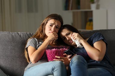 Two sad friends crying watching tv in the night Two sad friends crying watching tv in the night