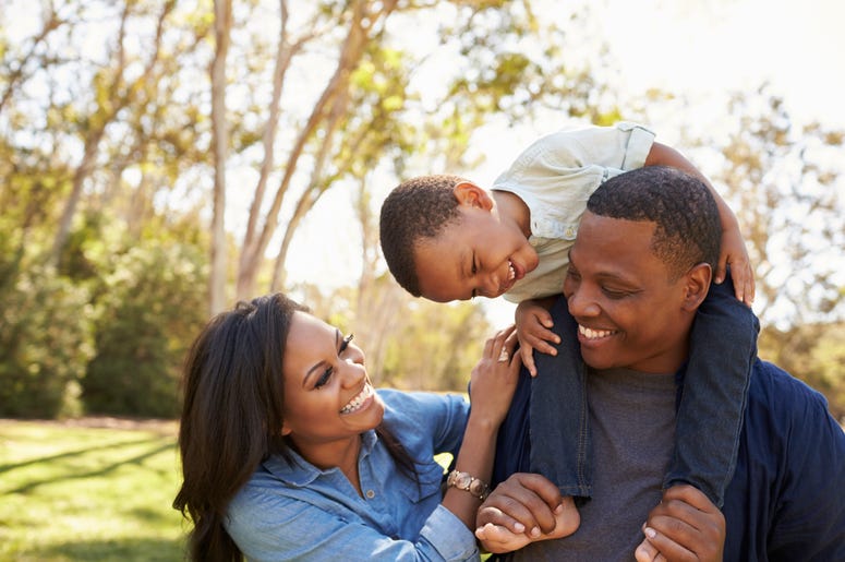 Celebrate Dad at Daddy Walk. Dad carries son on his back and mother smiles by his side.